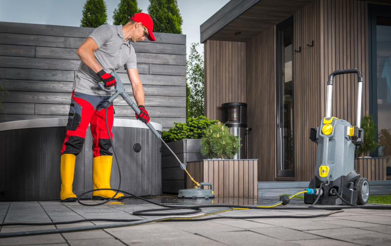 A man using a power washer on a patio
